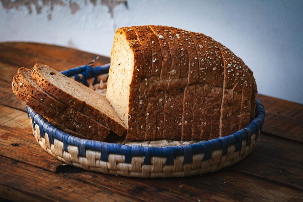 Artistic close-up of sliced whole wheat bread in a wicker basket on a rustic wooden table.