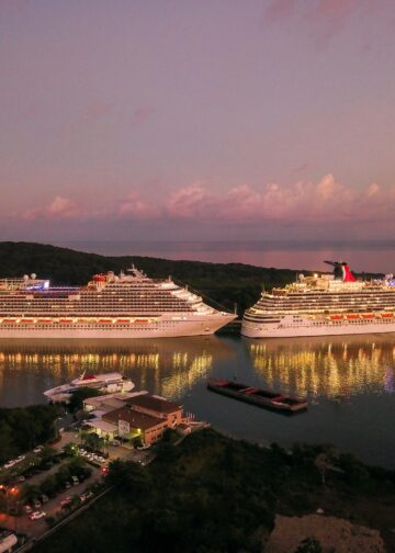 Two illuminated cruise ships docked at Coxen Hole, Honduras during twilight.