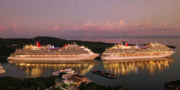 Two illuminated cruise ships docked at Coxen Hole, Honduras during twilight.
