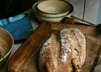 Rustic artisan bread placed on a wooden cutting board with vintage-style kitchenware.