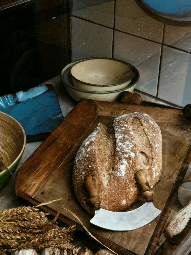 Rustic artisan bread placed on a wooden cutting board with vintage-style kitchenware.