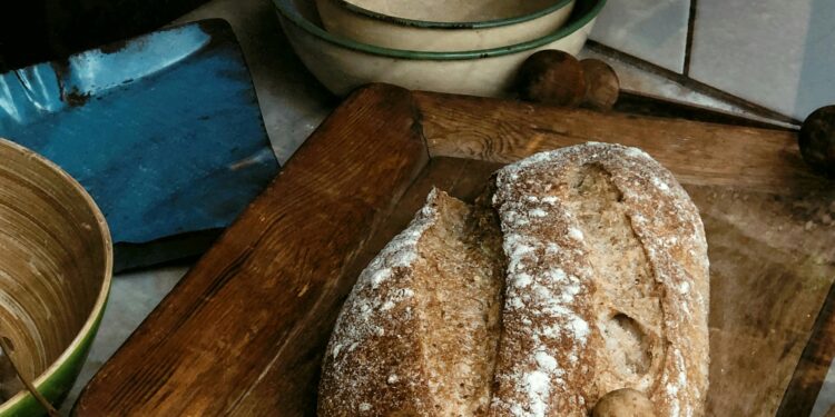 Rustic artisan bread placed on a wooden cutting board with vintage-style kitchenware.